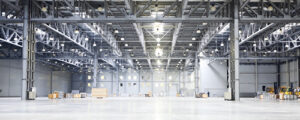 Large brightly lit open space warehouse with forklifts and large boxes to background