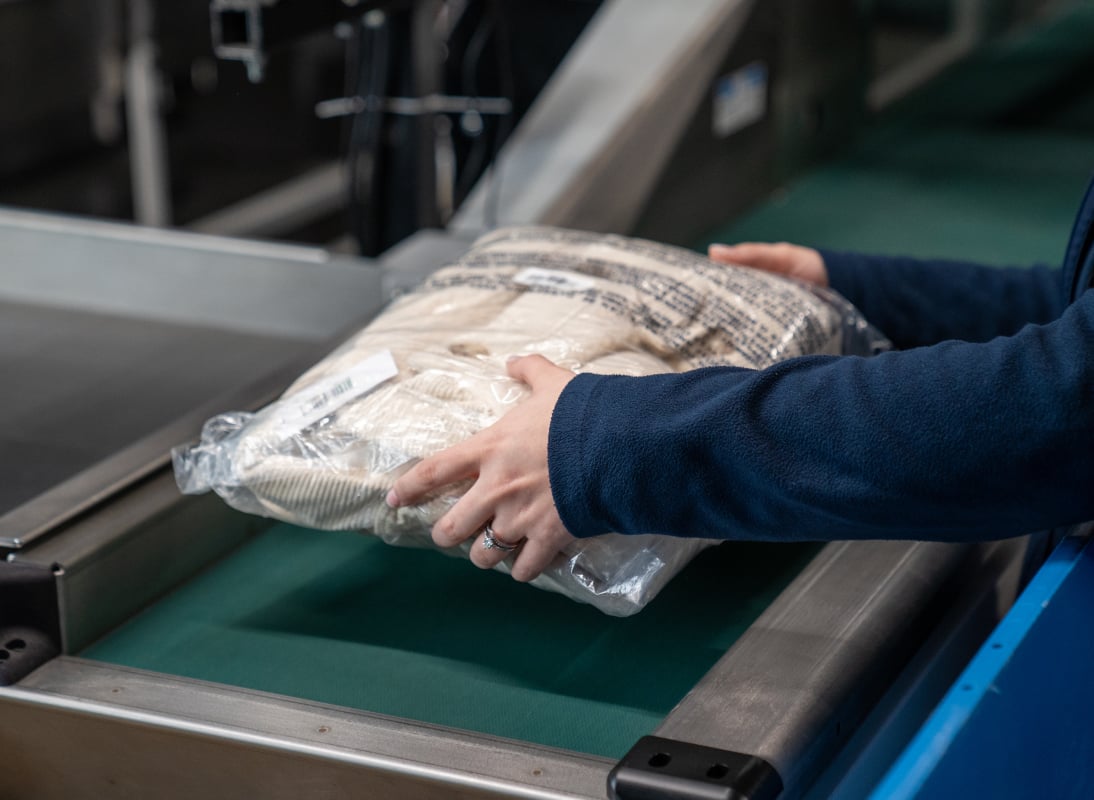 Person picking up wrapped product off of a conveyor belt